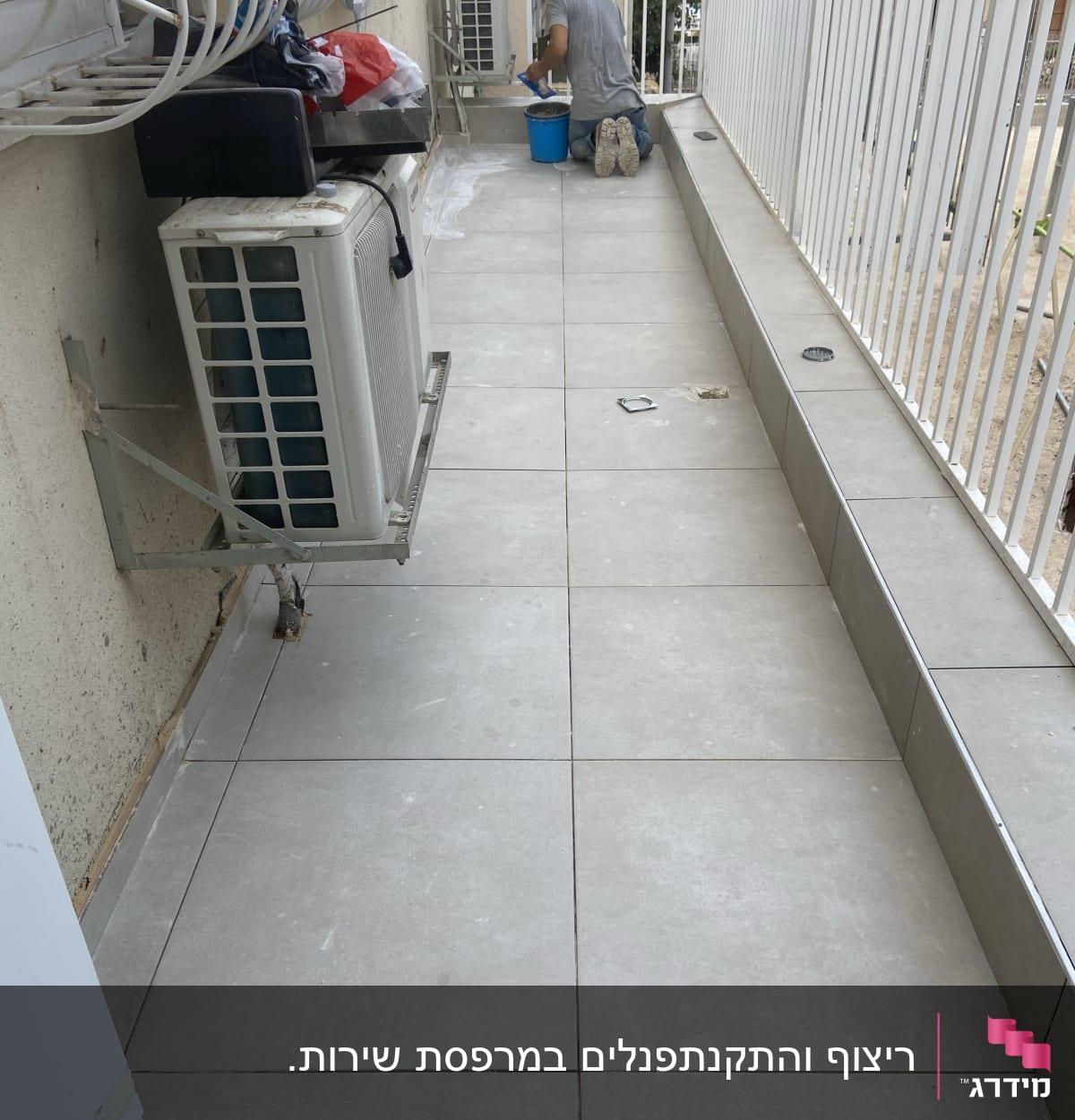 אדם עובד על רצפת מרפסת עם דלי כחול